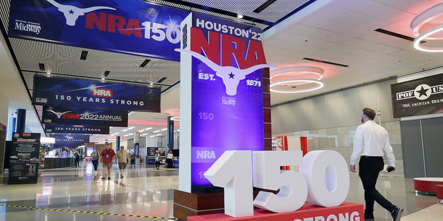 People walk past signage in the hallways outside of the exhibit halls at the NRA Annual Meeting held at the George R. Brown Convention Center on Thursday, May 26, in Houston, Texas.