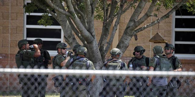 Law enforcement personnel stand outside Robb Elementary School following a shooting in Uvalde, Texas.