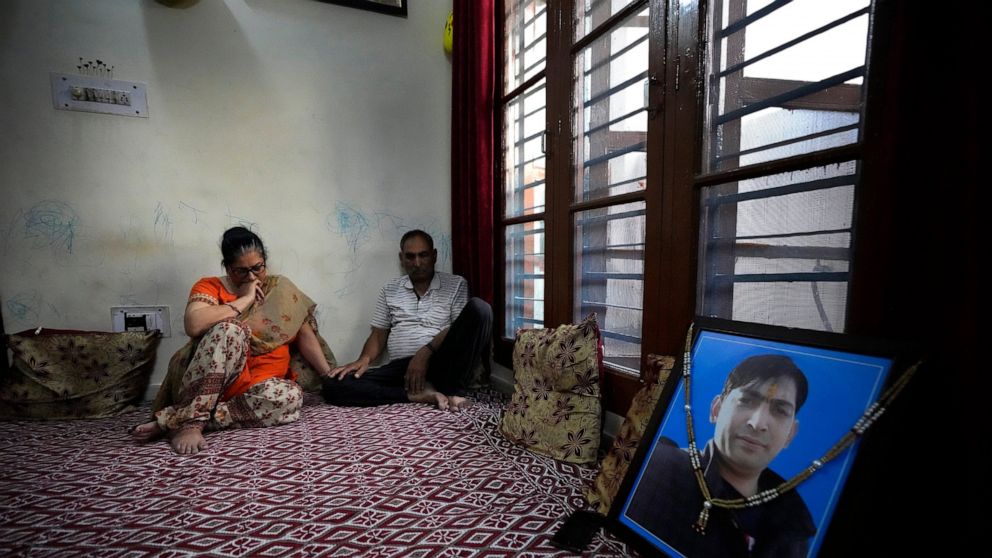 Usha Bhat, left, and Bitta Ji Bhat mourn by a photograph of their son Rahul Bhat at their residence in Jammu, India, June 11, 2022. Rahul Bhat, a Hindu revenue clerk, was fatally shot inside his office in Kashmir Valley in May. Two days later, police