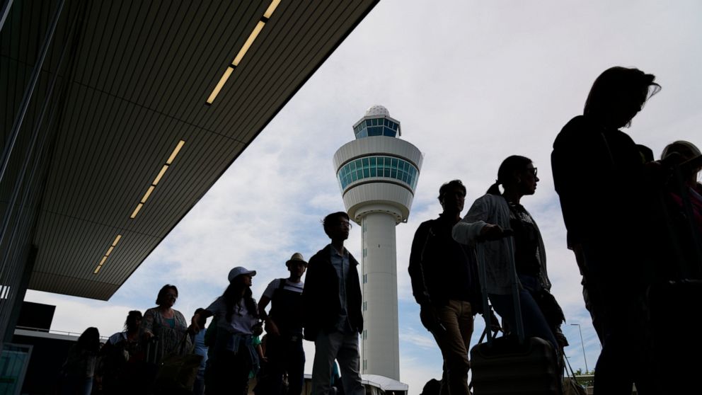 FILE - Travelers wait in long lines outside the terminal building to check in and board flights at Amsterdam's Schiphol Airport, Netherlands, Tuesday, June 21, 2022. After two years of pandemic restrictions, travel demand is back with a vengeance but