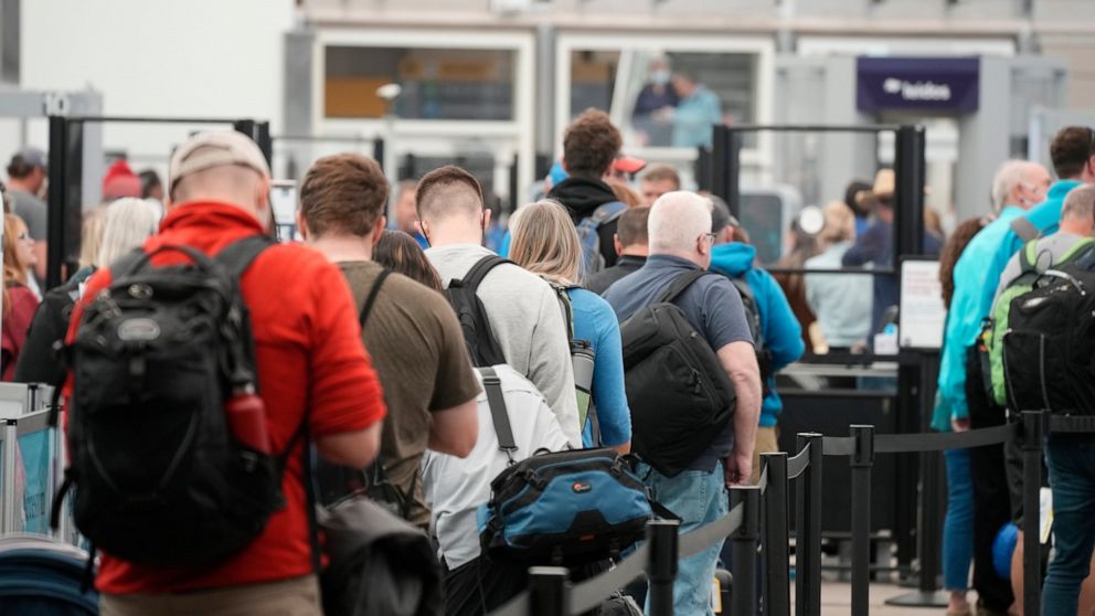 FILE - Travelers queue up at the north security checkpoint in the main terminal of Denver International Airport, Thursday, May 26, 2022, in Denver. Airlines canceled more than 1,000 flights by midmorning Friday, June 17, as they try to recover from s