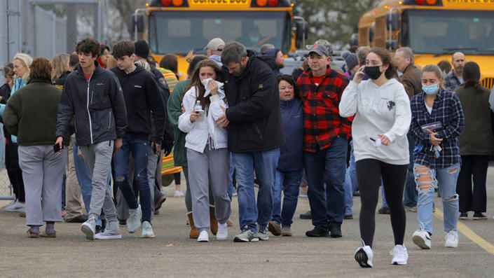 Parents walk away with their kids from the Meijer's parking lot in Oxford where many students gathered following an active shooter situation at Oxford High School in Oxford on November 30, 2021. <span class="copyright">Eric Seals-USA TODAY NETWORK</span>