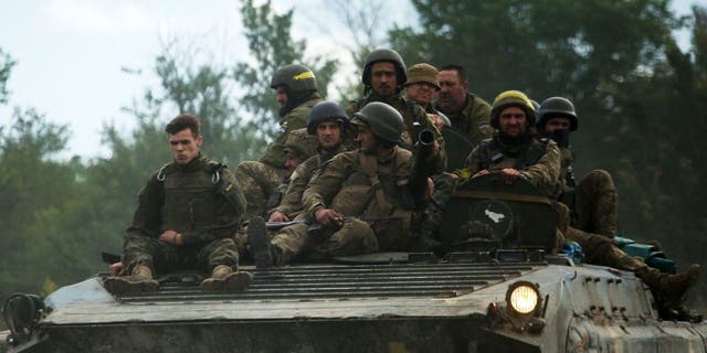 Ukrainian soldiers ride on an armored personnel carrier (APC) on a road of the eastern Luhansk region on June 23, 2022, amid Russia's military invasion launched on Ukraine. On the road between the towns of Siversk and Bakhmut, AFP journalist witnessed several shellings on the route, which is now the main itinerary being used to reach the city of Lysychansk.