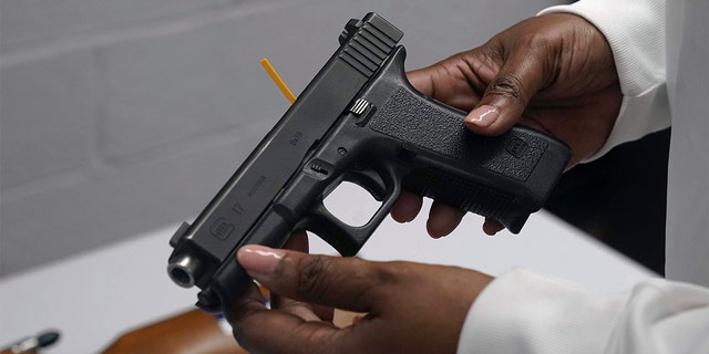 FILE - A handgun from a collection of illegal guns is reviewed during a gun buyback event in Brooklyn, N.Y., May 22, 2021.