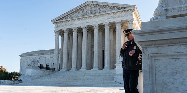 A police officer maintains a watch during a demonstration by victims of gun violence in front of the Supreme Court. 