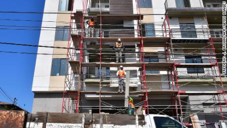 Construction workers pass planks of wood during the construction of new apartments in Monterey Park, California.