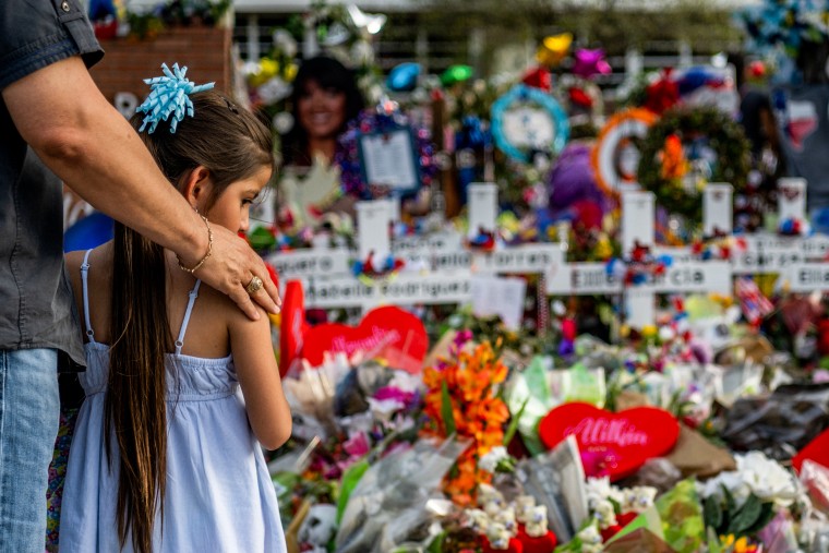 Seth Garza pays his respects with his daughter Lilly at a memorial on May 31, 2022, dedicated to the 19 children and two adults killed in the mass shooting at Robb Elementary School in Uvalde, Texas.