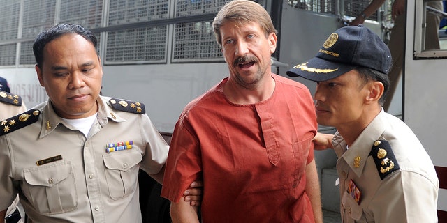 Alleged Russian arms dealer Viktor Bout is escorted by policemen as he arrives for a hearing at the Criminal Court in Bangkok.