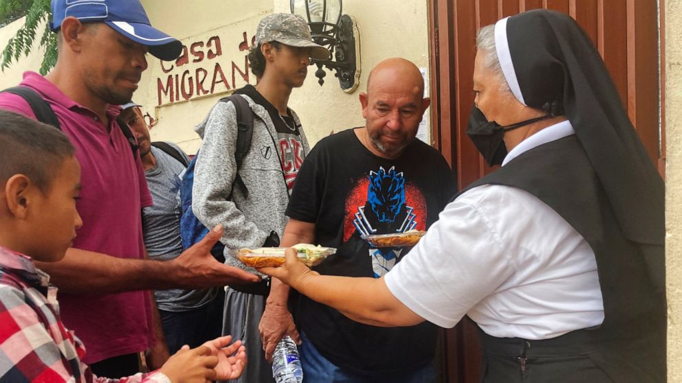 Isabel Turcios, director of the Casa del Migrante migrant services center delivers breakfasts of rice, beans and tortillas to migrants lined up outside, June 1, 2022 in Piedras Negras, Mexico. (AP Photo/Elliot Spagat)