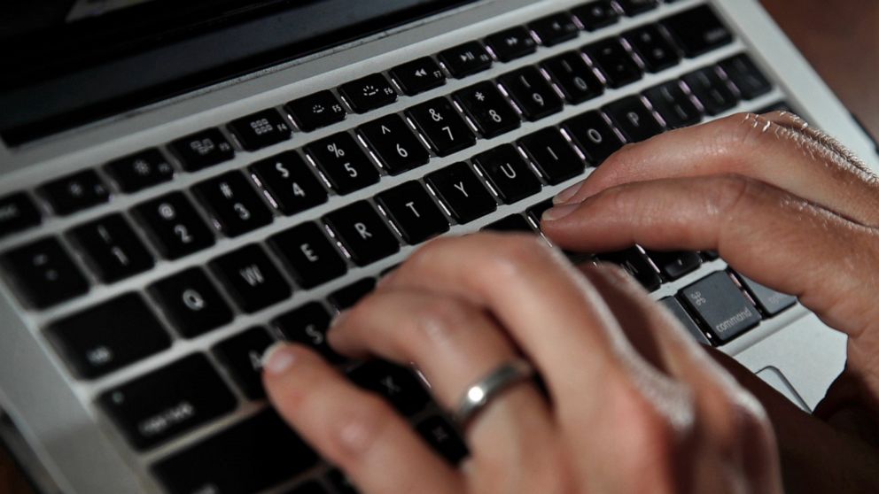 FILE- In this June 19, 2017, file photo, a person types on a laptop keyboard in North Andover, Mass. The availability of remote work has increased significantly in recent years, giving rise to the ability for telecommuters to buck travel norms. Remot