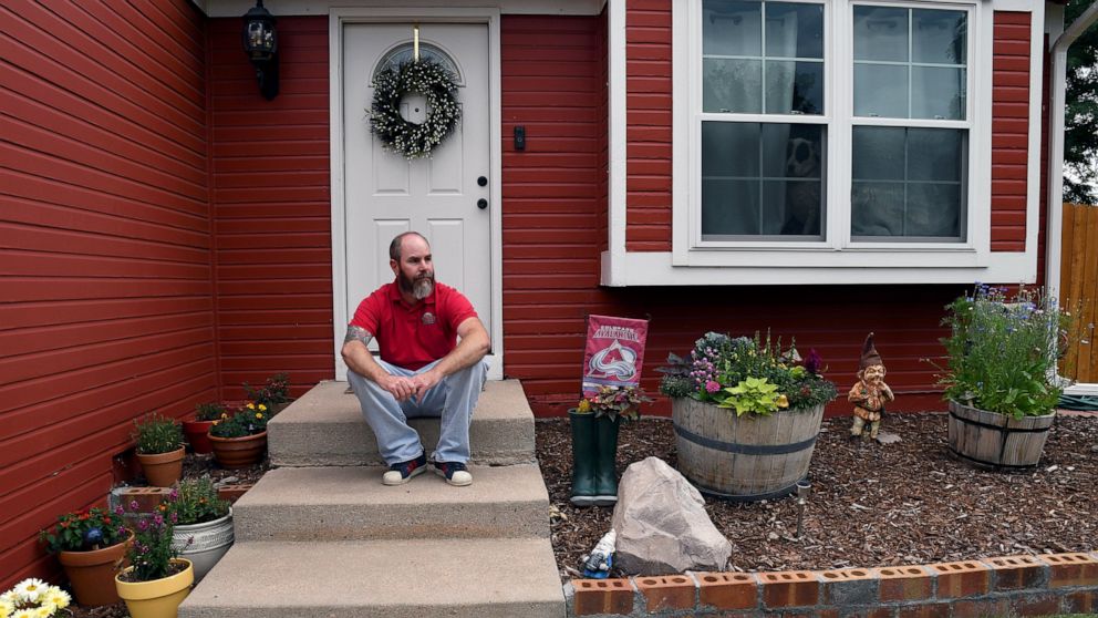 Kyle Tomcak sits in front of his house in Aurora, Colo., on Monday, July 18, 2022. Tomcak was in the market for a home priced around $450,000 for his in-laws and he and his wife bid on every house they toured, regardless of whether they fell in love