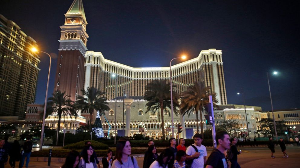 FILE - People walk in front of the Venetian Macao casino resorts in Macao, Nov. 23, 2014. The Asian gambling center of Macao will close all its casinos for a week starting Monday, July 11, and largely restrict people to their homes as it tries to sto