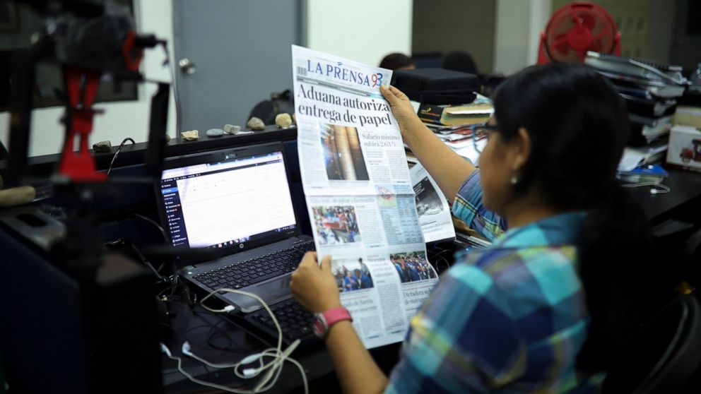 FILE - A journalist holds up a copy of La Prensa independent newspaper with a headline that reads in Spanish; "Customs authorizes release of printing paper," in Managua, Nicaragua, Friday, Feb. 7, 2020. La Prensa, the country´s oldest and most influe