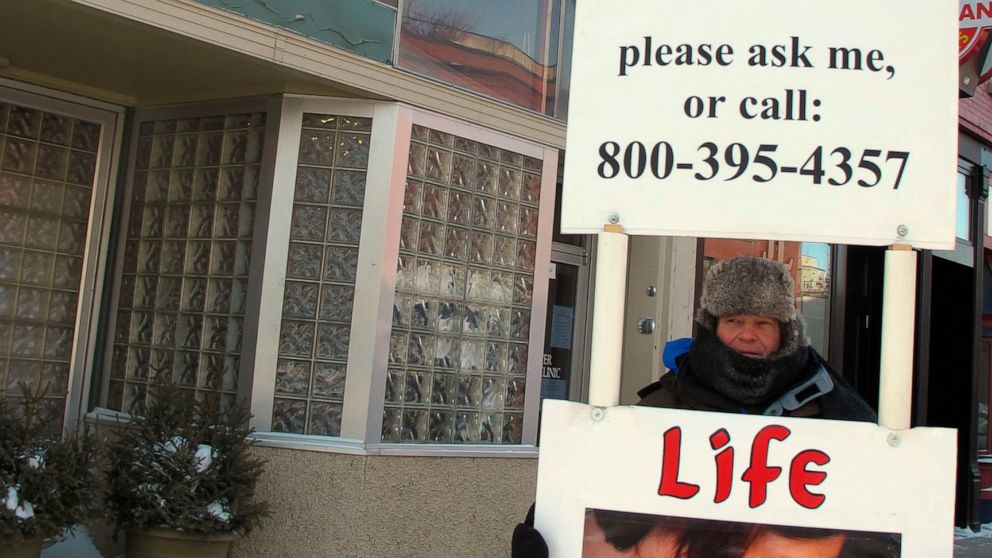 FILE - An abortion protester stands outside the Red River Valley Women's Clinic in Fargo, N.D., on Feb. 20, 2013. North Dakota's only abortion clinic, the Red River Women's Clinic, has gone to federal court seeking to declare the state's imminent abo