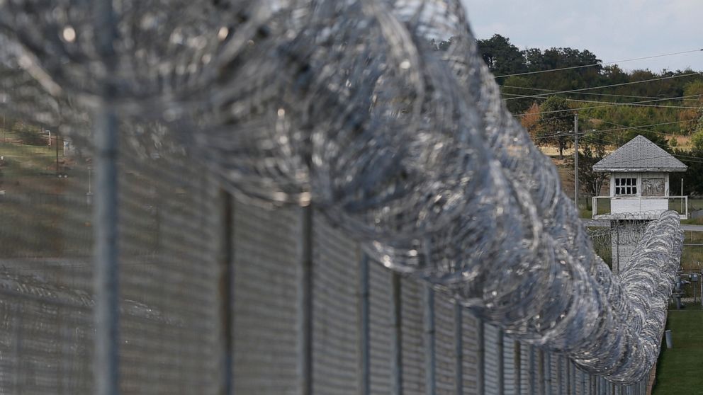 FILE This Thursday, Oct. 9, 2014, file photo, shows fencing and an old guard tower at the Oklahoma State Penitentiary in McAlester, Okla. Contraband including weapons, cellphones, drones and grappling hooks believed to be headed to state prisons was