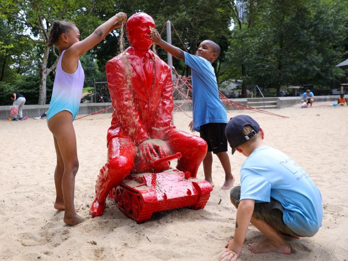 Children put sand on a statue of Russian President Vladimir Putin riding a tank created by French artist James Colomina in Central Park in Manhattan, New York City, U.S., August 2, 2022.