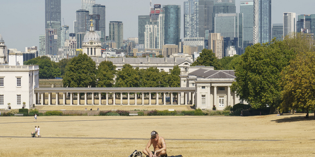 A man sunbathes in a nearly empty Greenwich Park in London on Sunday Aug. 14.