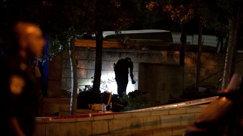 An Israeli police crime scene investigator works at the scene of a shooting attack that wounded several Israelis near the Old City of Jerusalem, early Sunday, Aug. 14, 2022. Israeli police and medics say a gunman opened fire at a bus in a suspected P