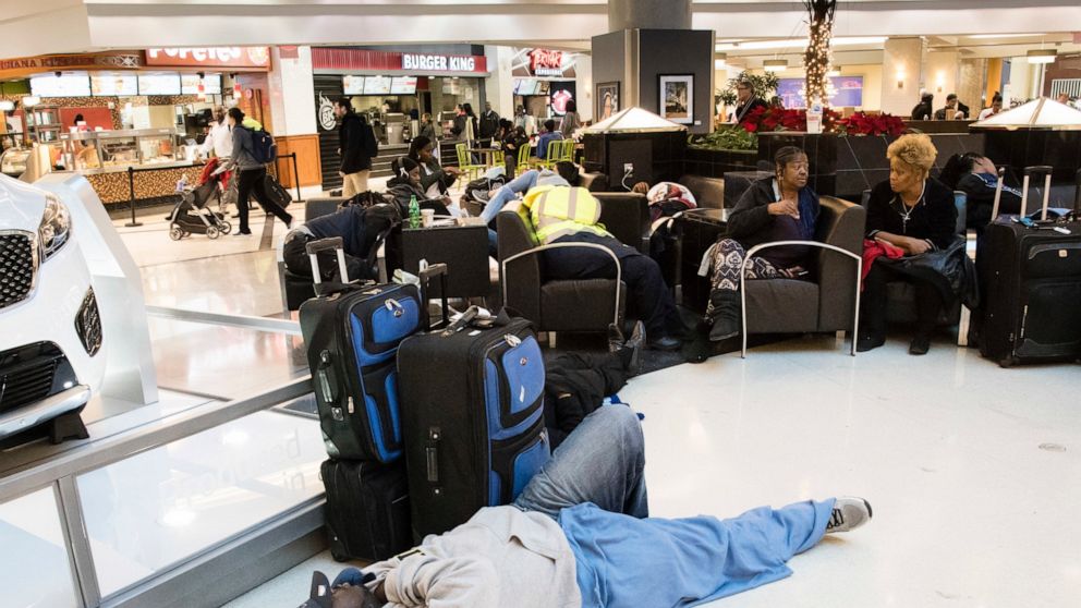 FILE - A man sleeps on the terminal floor at Hartfield-Jackson Atlanta International Airport on Dec. 18, 2017, in Atlanta. Transportation Secretary Pete Buttigieg has warned airlines that his department could draft new rules around passenger rights i