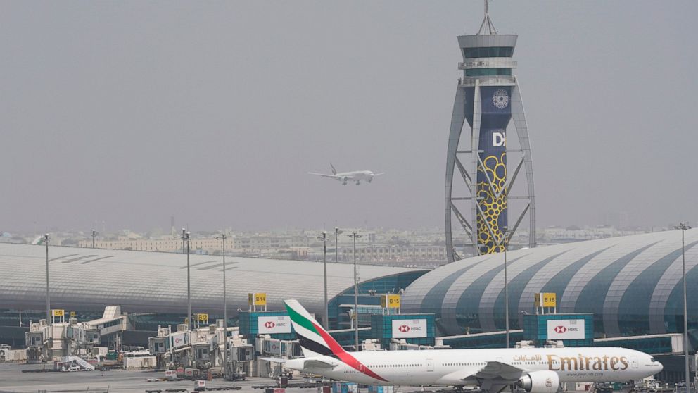 An Emirates Boeing 777 stands at the gate at Dubai International Airport as another prepares to land on the runway in Dubai, United Arab Emirates, Wednesday, Aug. 17, 2022. Dubai International Airport saw a surge in passengers over the first half of