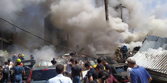 Smoke rises from Surmalu market about two kilometers (1.2 miles) south of the center Yerevan, Armenia, Sunday, Aug. 14, 2022. A strong explosion hit a large market in the capital of Armenia on Sunday, setting off a fire and reportedly trapping people under rubble. The Interfax news agency cited Armenia's emergency service as saying the explosion occurred in a building at the Surmalu market where fireworks were sold. (AP Photo/Daniel Bolshakov)