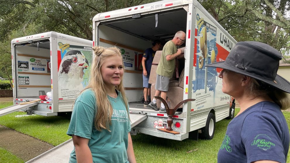 Medical student Emily Davis, left, speaks with her landlord Suzannah Thames on Friday, Aug. 26, 2022, as workers move furniture, appliances and other belongings out of a home Davis and her husband are renting in a flood-prone area of Jackson, Miss. A