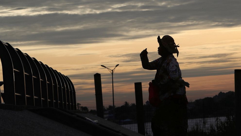 A woman is silhouetted as she walks up riverside stairs near a hotel where Cambodia's set the 55th ASEAN Foreign Ministers' Meeting (55th AMM) in Phnom Penh, Cambodia, Tuesday, Aug. 2, 2022. (AP Photo/Heng Sinith)