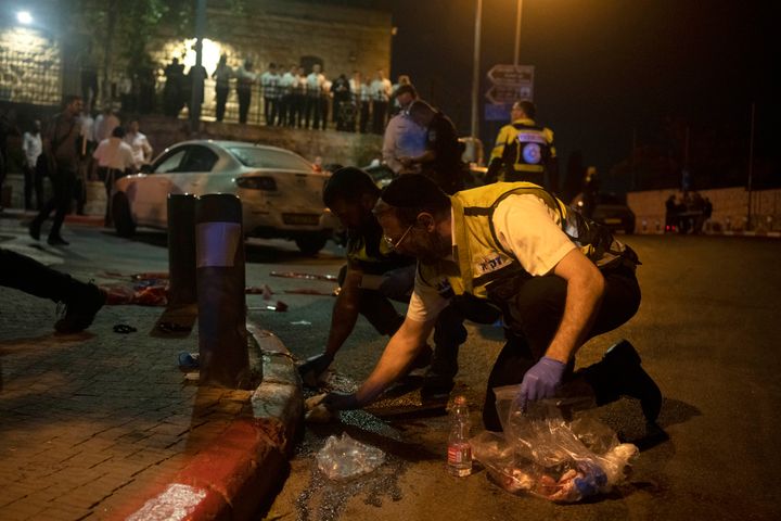 Volunteers with Zaka rescue service clean blood from the scene of a shooting attack that wounded several Israelis near the Old City of Jerusalem, early Sunday, Aug. 14, 2022. (AP Photo/ Maya Alleruzzo)