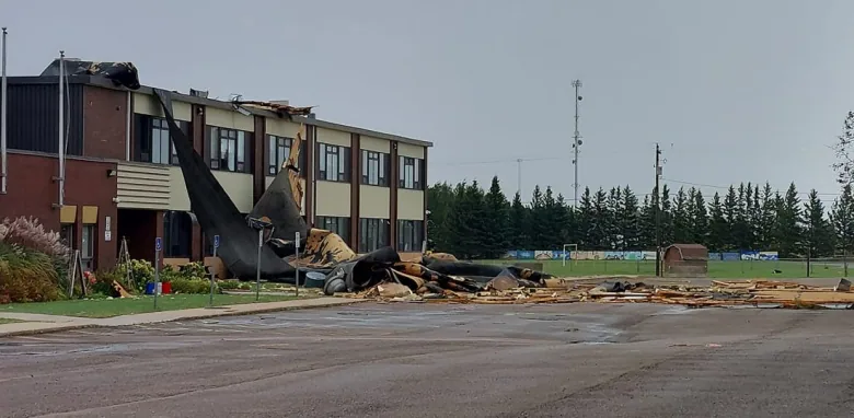 School building with large chunks of its roof torn off and hanging down. 