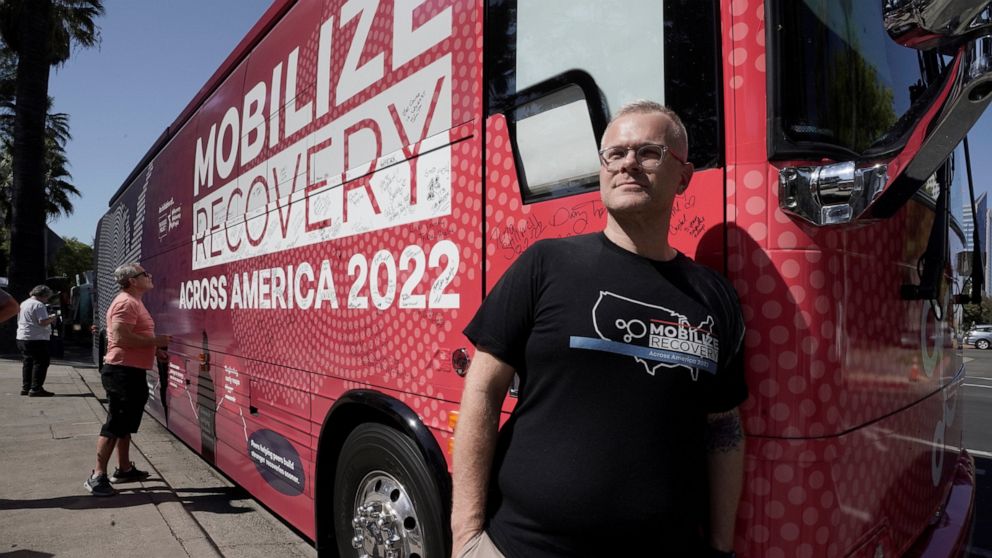 Ryan Hampton, founder of the Voices Project, poses outside the 2022 Mobile Recovery National Bus during a stop in Sacramento, Calif., Wednesday, Sept. 7, 2022. Across the country, people in recovery and relatives of those killed by opioid overdoses a