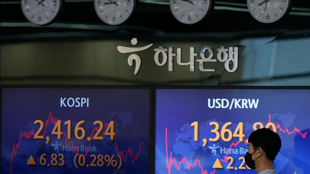 A currency trader walks by the screens showing the Korea Composite Stock Price Index (KOSPI), left, and the foreign exchange rate between U.S. dollar and South Korean won at a foreign exchange dealing room in Seoul, South Korea, Monday, Sept. 5, 2022