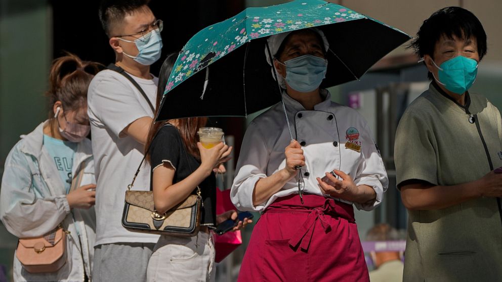 People wearing face masks wait in line to get their routine COVID-19 throat swabs at a coronavirus testing site in Beijing, Monday, Sept. 5, 2022. (AP Photo/Andy Wong)