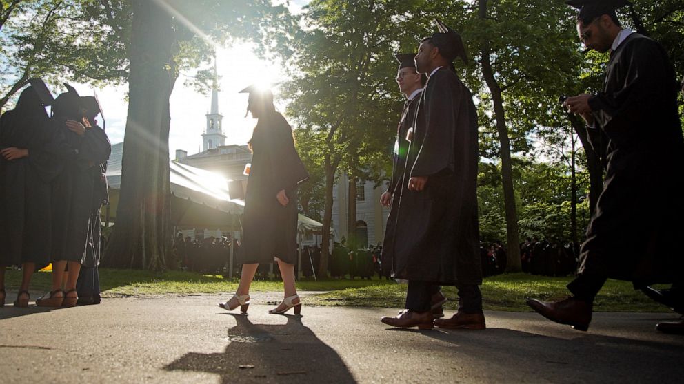 FILE - Graduates walk at a Harvard Commencement ceremony held for the classes of 2020 and 2021, Sunday, May 29, 2022, in Cambridge, Mass. The Department of Education says borrowers who hold eligible federal student loans and have made voluntary payme