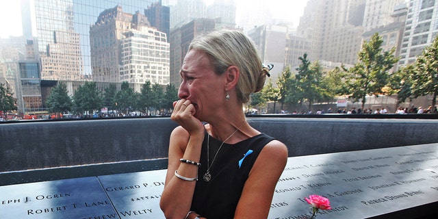 NEW YORK, NY - SEPTEMBER 11: Carrie Bergonia of Pennsylvania looks over the name of her fiance, firefighter Joseph Ogren, at the 9/11 Memorial during ceremonies for the twelfth anniversary of the terrorist attacks in lower Manhattan at the World Trade Center site on September 11, 2013, in New York City.