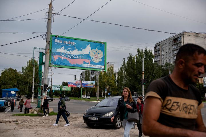 People walk in a street with a billboard that reads: "Our choice - Russia", prior to a referendum in Luhansk, Luhansk People's Republic controlled by Russia-backed separatists, eastern Ukraine, on Sept. 22, 2022.