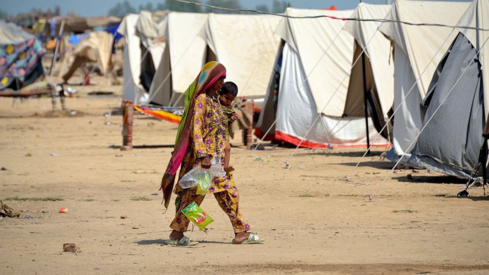 A woman walks at a camp as she take a refuge after leaving her flood-hit homes, in Jaffarabad, a district of Baluchistan province, Pakistan, Wednesday, Sept. 21, 2022. Devastating floods in Pakistan's worst-hit province have killed 10 more people in