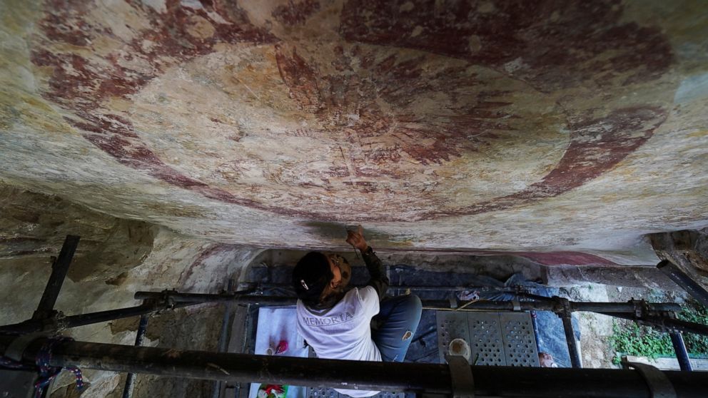 Valeria Lopez restores a mural at the 1550s-era convent convent of Tepoztlan in Morelos state, Mexico, Friday, Oct. 7, 2022. Indigenous symbols were found painted next to Roman Catholic motifs at this convent near Mexico City. (AP Photo/Marco Ugarte)