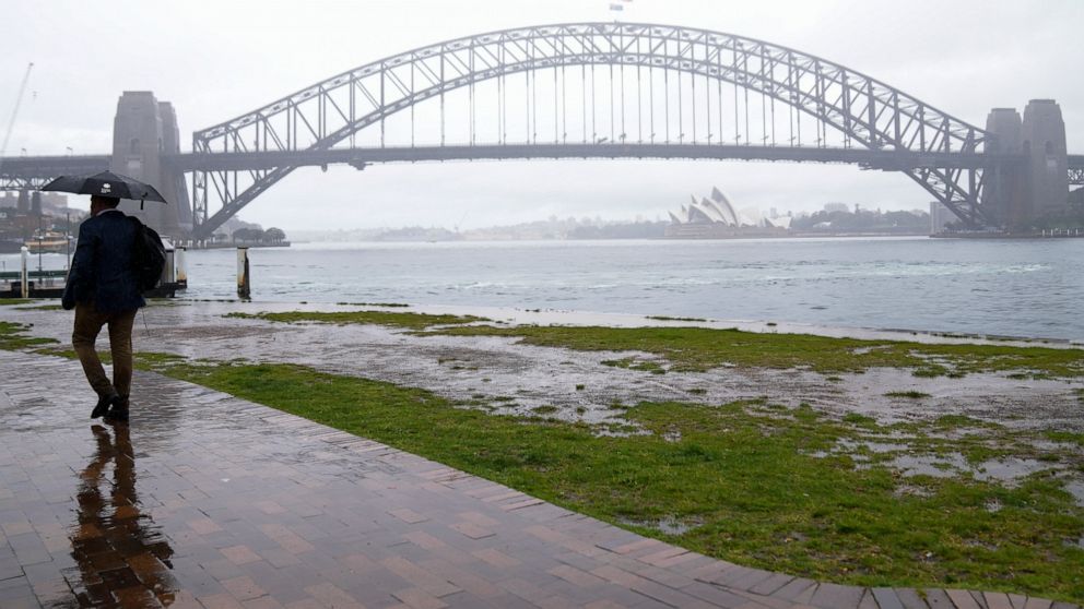 A commuter waits in the rain in Sydney, Australia, Thursday, Oct. 6, 2022. Sydney notched up its wettest year in over 160 years of records, Weatherzone's Andrew Miskelly said, recording 2199.8mm at 1.10pm. The previous record was 2194mm in 1950. (AP