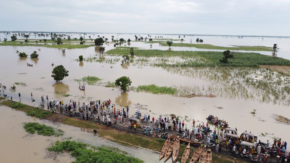 FILE - People walk through floodwaters with flooded farmlands forground after heavy rainfall in Hadeja, Nigeria, Sept 19, 2022. West and Central African countries are battling deadly floods that have upended lives and livelihoods, raising fears of fu