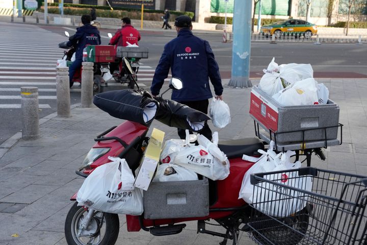 Delivery men prepare to deliver their orders for a supermarket in Beijing, on Nov. 25, 2022. 