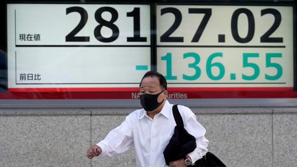 A person wearing a protective mask walks in front of an electronic stock board showing Japan's Nikkei 225 index at a securities firm Monday, Nov. 14, 2022, in Tokyo. Asian shares were mixed in Monday trading, as some momentum of a rally on Wall Stree