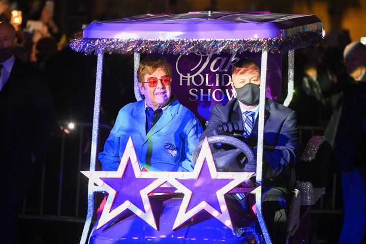 Elton John arrives at Saks Fifth Avenue in New York City on Tuesday, riding in a golf cart themed around his unique style.
