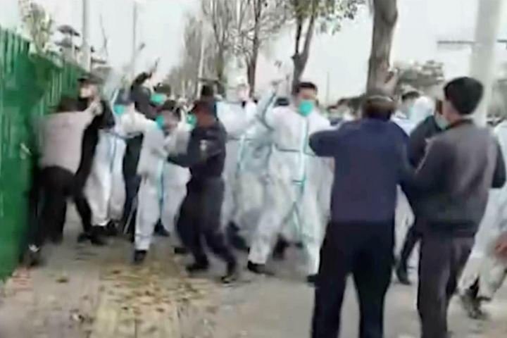 In this photo provided Nov 23, 2022, security personnel in protective clothing attack a man during protest at the factory compound operated by Foxconn Technology Group who runs the world's biggest Apple iPhone factory in Zhengzhou in central China's Henan province. Employees at the world's biggest Apple iPhone factory were beaten and detained in protests over pay amid anti-virus controls, according to witnesses and videos on social media Wednesday, as tensions mount over Chinese efforts to combat a renewed rise in infections. (AP)