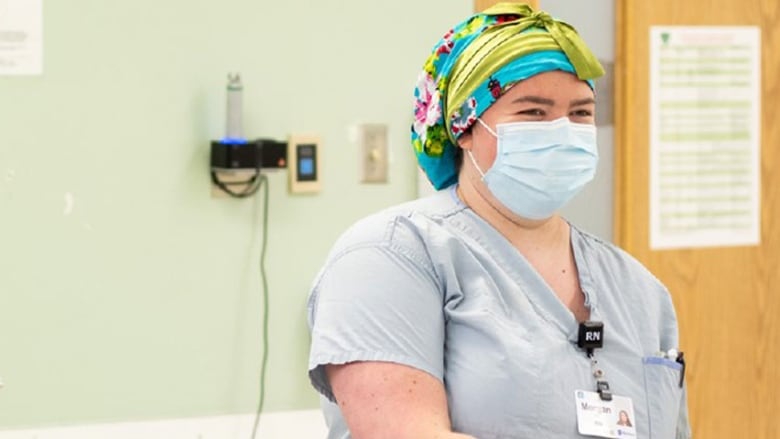 A portrait of a woman wearing surgical scrubs and a surgical mask.