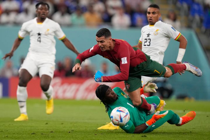 Portugal's Cristiano Ronaldo, up, falls over Ghana's goalkeeper Lawrence Ati-Zigi during the World Cup group H soccer match between Portugal and Ghana, at the Stadium 974 in Doha, Qatar, Thursday, Nov. 24, 2022. (AP Photo/Darko Bandic)