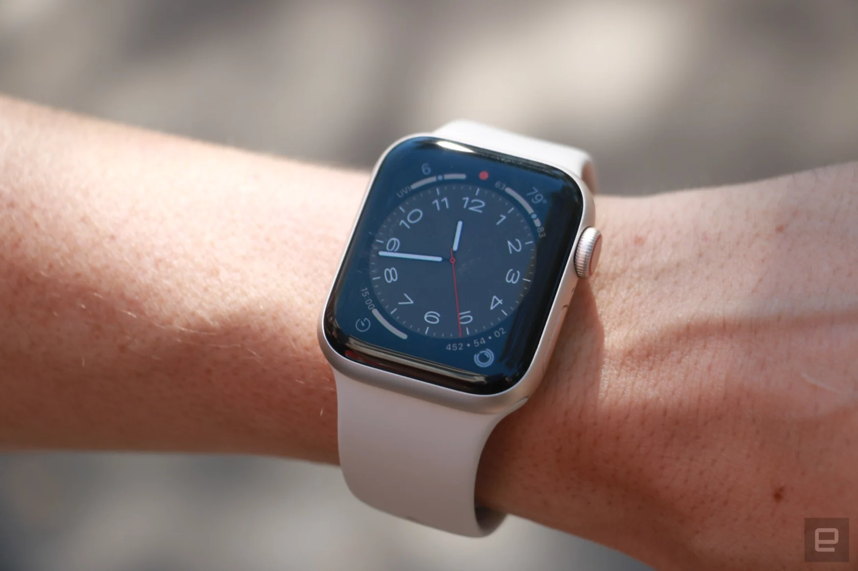 The Apple Watch SE (2022) with a starlight case and starlight band, on a person's wrist.