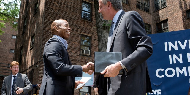 Public housing residents watch then-New York City Mayor Bill DeBlasio and Brooklyn borough president Eric Adams speak at a ceremony for the groundbreaking of a new community center in the Marcy Houses on June 11, 2018, in Brooklyn, New York.