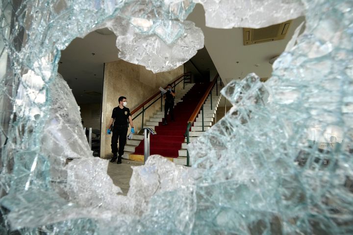 Forensic investigators are framed by a cracked window damaged when supporters of Brazil's former President Jair Bolsonaro stormed the Brazilian Supreme Court building, in Brasilia, Brazil, Tuesday, Jan. 10, 2023. Bolsonaro supporters who refuse to accept his election defeat stormed Congress, the Supreme Court and presidential palace Sunday, a week after the inauguration of his leftist rival, President Luiz Inacio Lula da Silva. (AP Photo/Eraldo Peres)