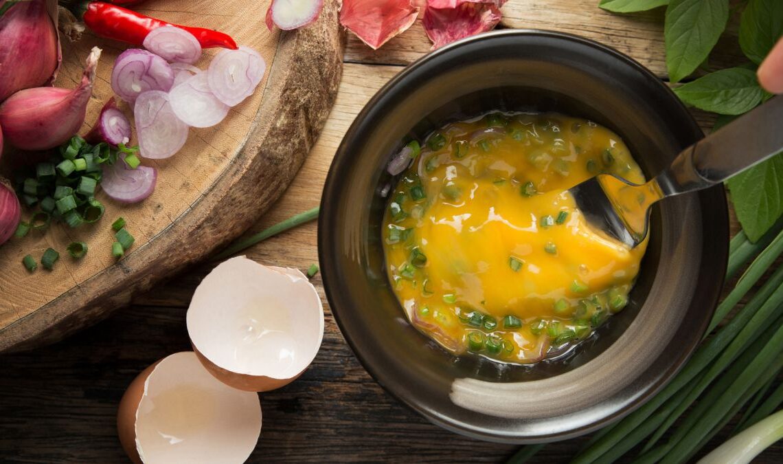 raw eggs and chives in a black bowl