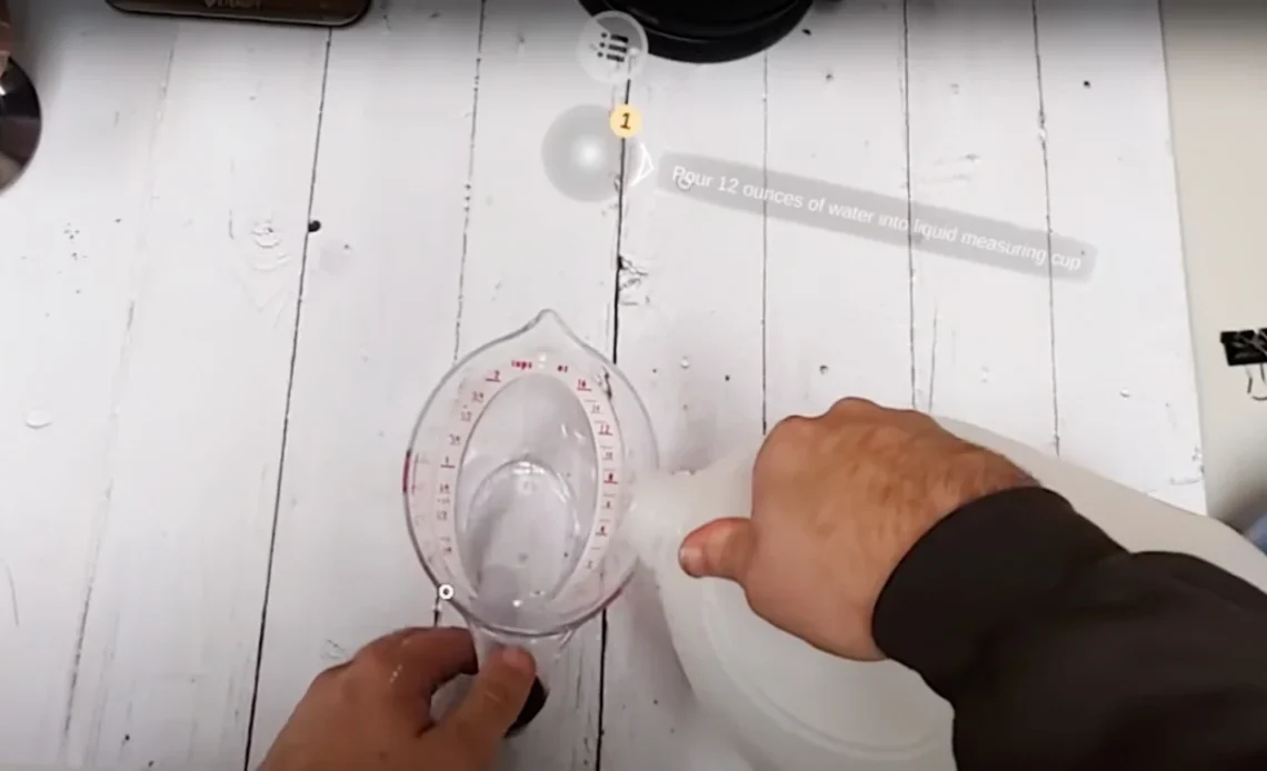 First-person view of a person pouring liquid from a plastic jug into a measuring cup. AR instructions to “Pour 12 ounces of water into liquid measuring cup” are overlaid onto their field of view.